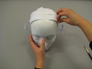 Stripes of paper being placed on top of mannequin head